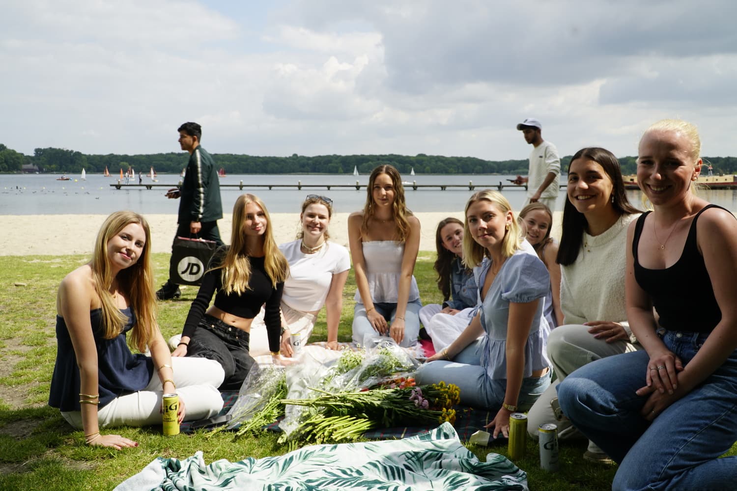 Group of people sitting on grass near water